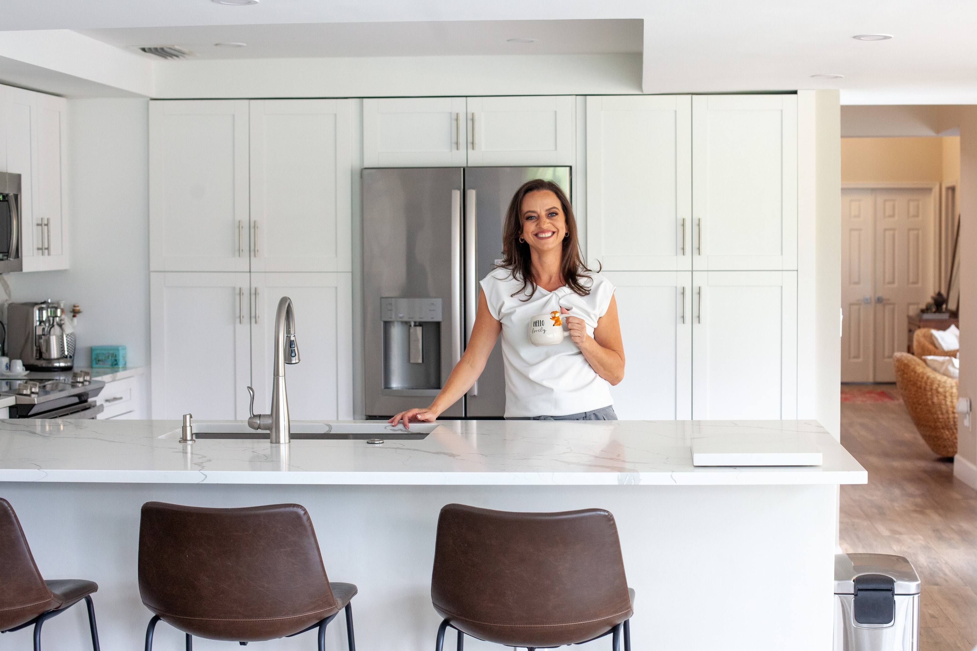 Anaie Amorim smiling at a kitchen island, holding a coffee mug